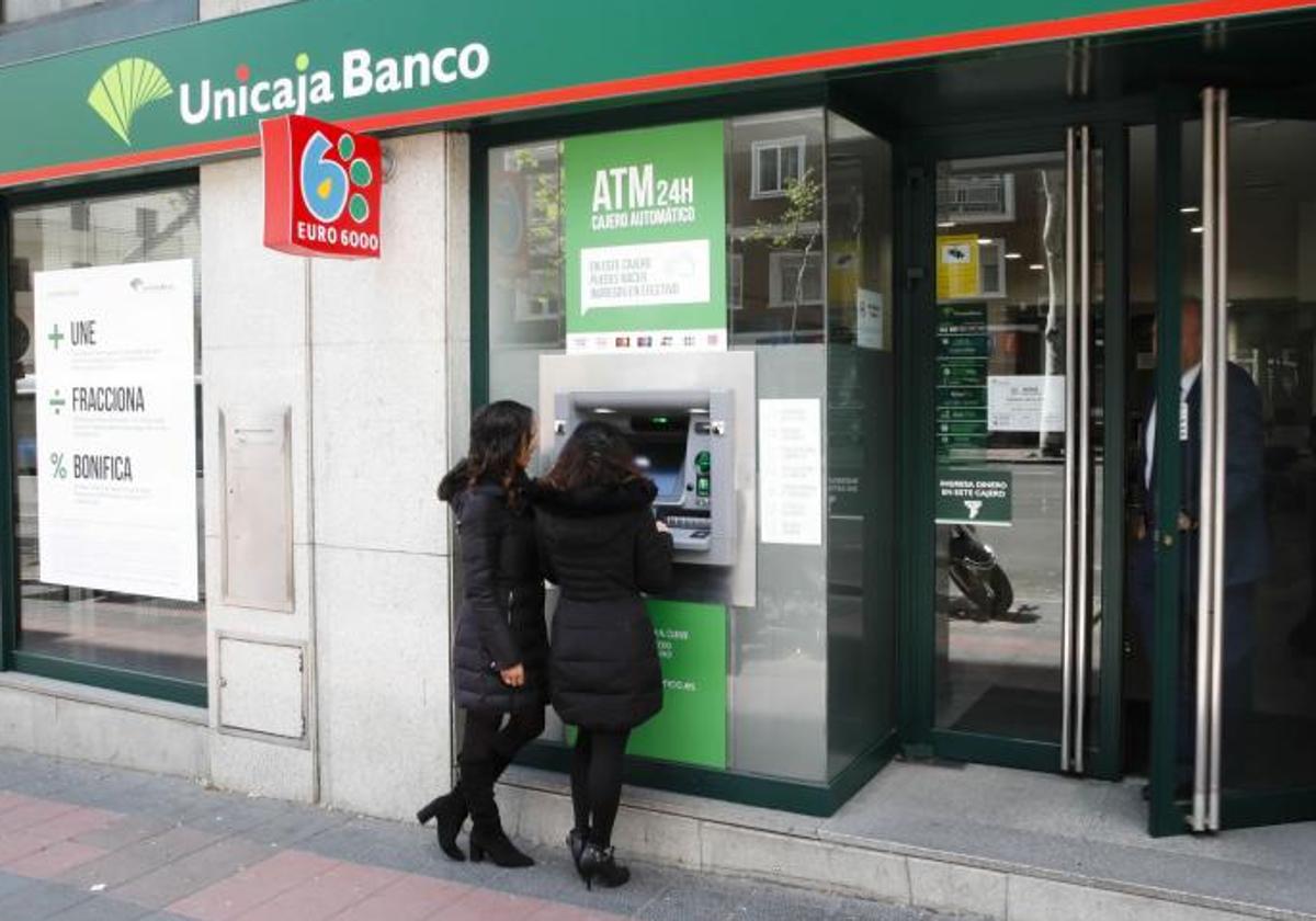 Clientes hacen gestiones en una oficina de Unicaja Banco.