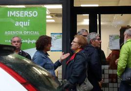 Varias personas hacen cola a la puerta de una agencia de viajes para contratar viajes del Imserso.