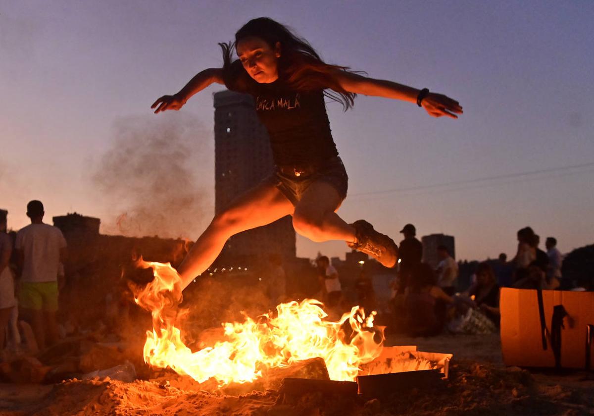 Una joven salta la hoguera de San Juan en la playa de Las Moreras.