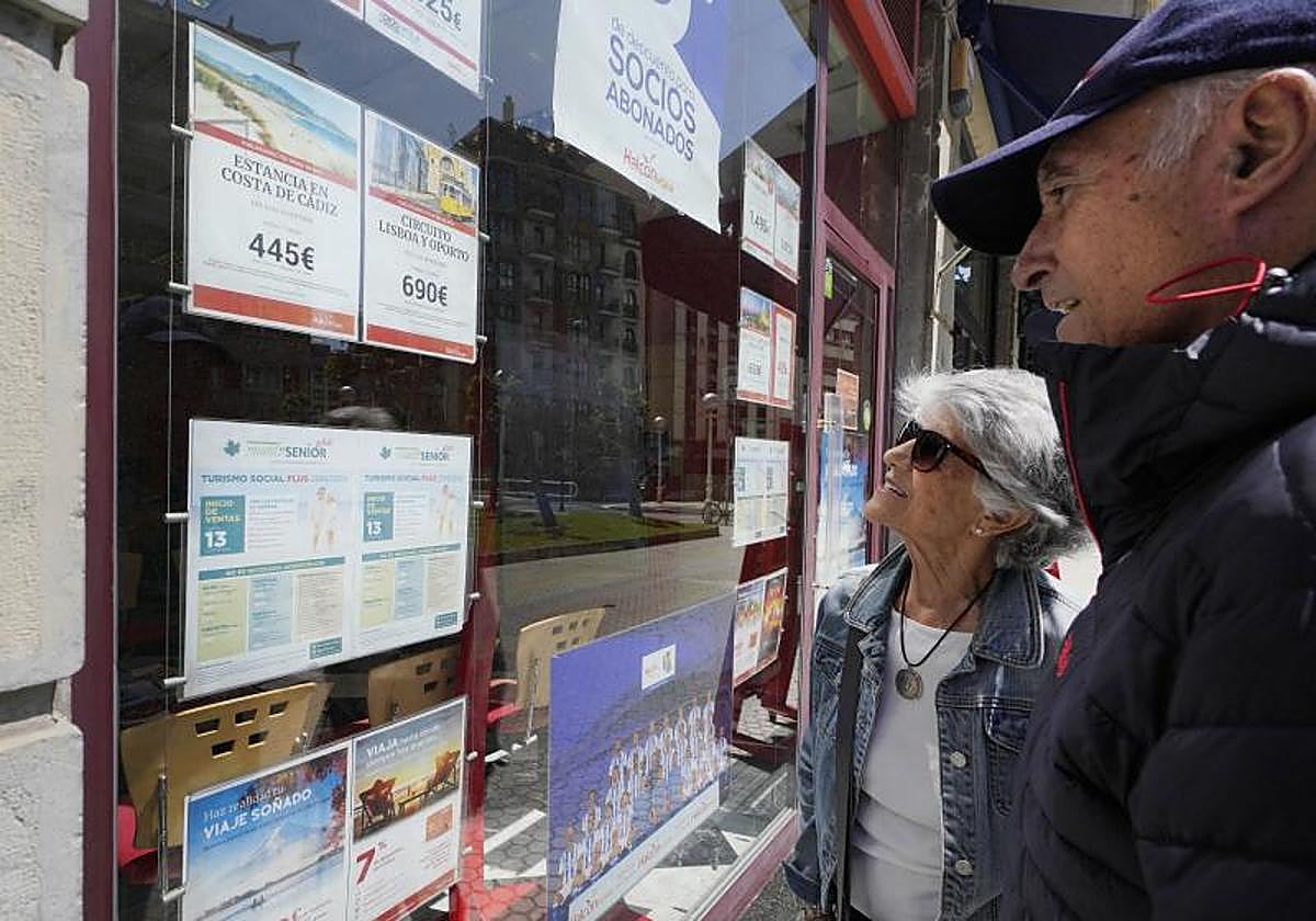 Una pareja de jubilados observa las ofertas de una agencia de viajes.