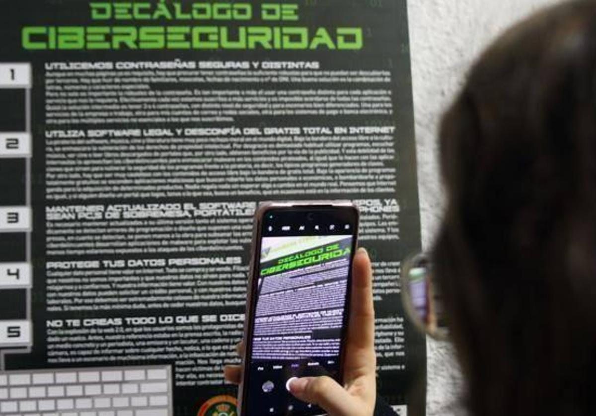 Una persona hace una fotografía de un cartel de recomendaciones sobre ciberseguridad.