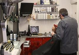 Un peluquero corta el pelo a uno de sus clientes en su local de Segovia.