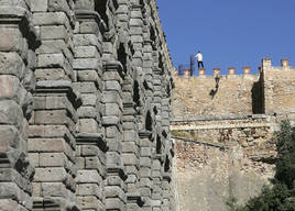 Un hombre, subido a la muralla junto al Acueducto en la zona del Postigo.