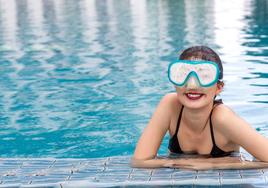 Una joven se cubre los ojos con unas gafas de buceo en una piscina.