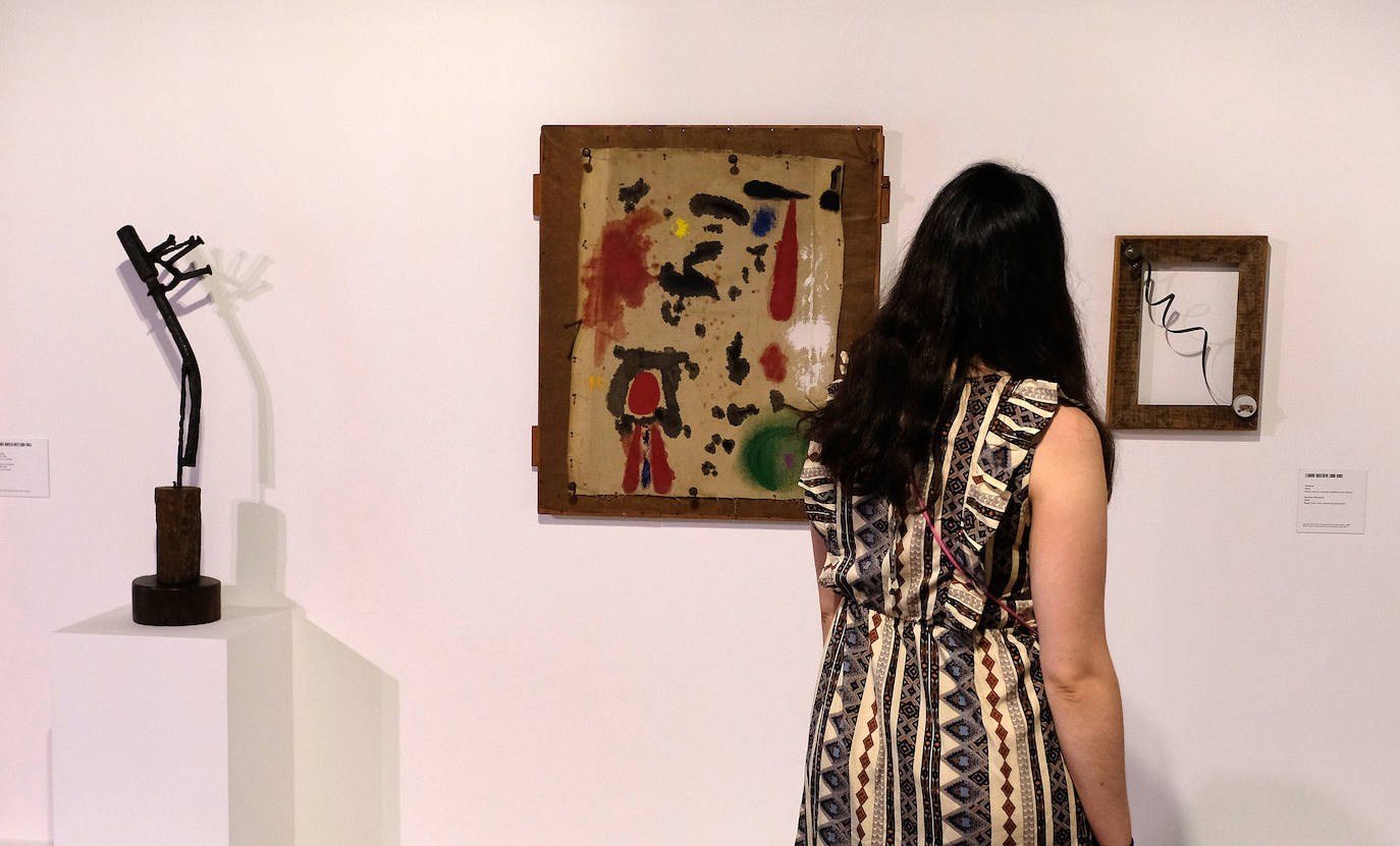 Una visitante ante la pintura 'Objeto', de Joan Miró, y esculturas creadas con materiales de desecho.