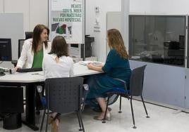 Dos mujeres son atendidas por una empleada de una entidad bancaria.