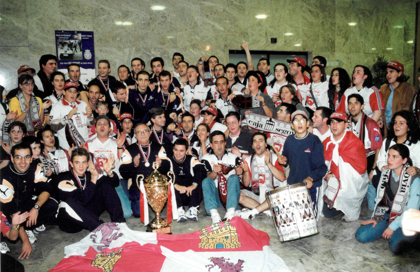 Aficionados y jugadores posan con la copa del mundo a la llegada de los jugadores al aeropuerto de Barajas
