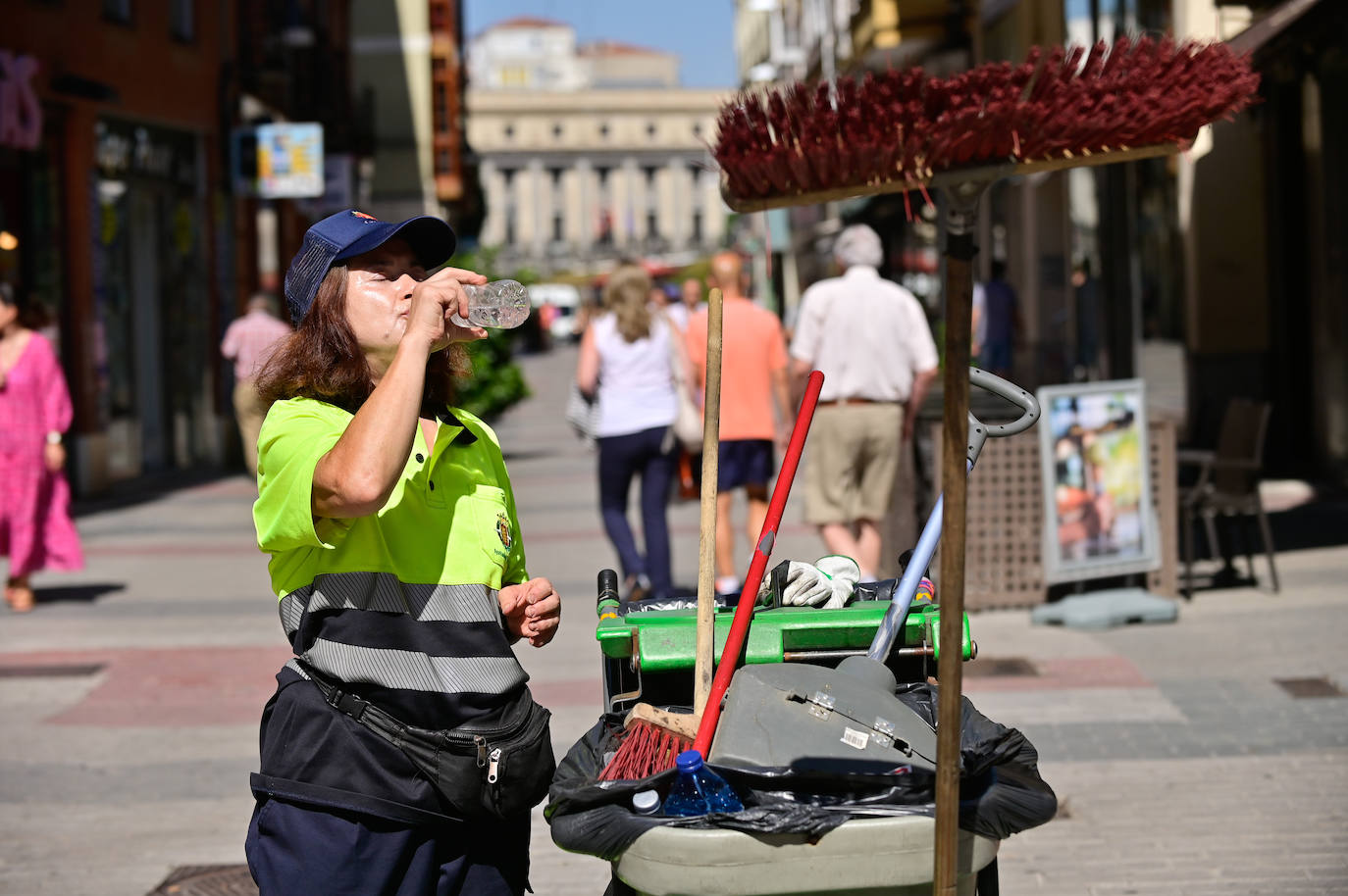 Una trabajadora de la limpieza se hidrata en una calle del centro de Valladolid.