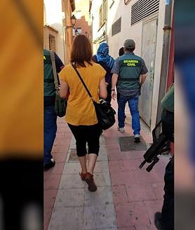 Imagen secundaria 2 - Una bandera incautada durente los registros y los agentes acompañan a la detenida.