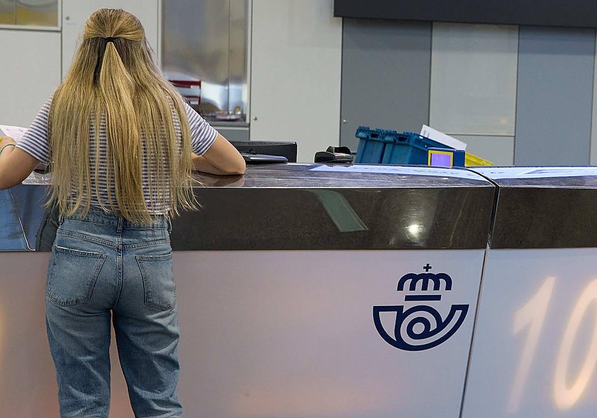 Una mujer solicita el coto por correo en una oficina de Correos.