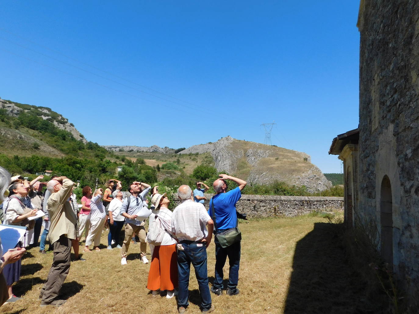 Un grupo de cursillistas del románico observa detalles una ermita siguiendo la explicación del guía.