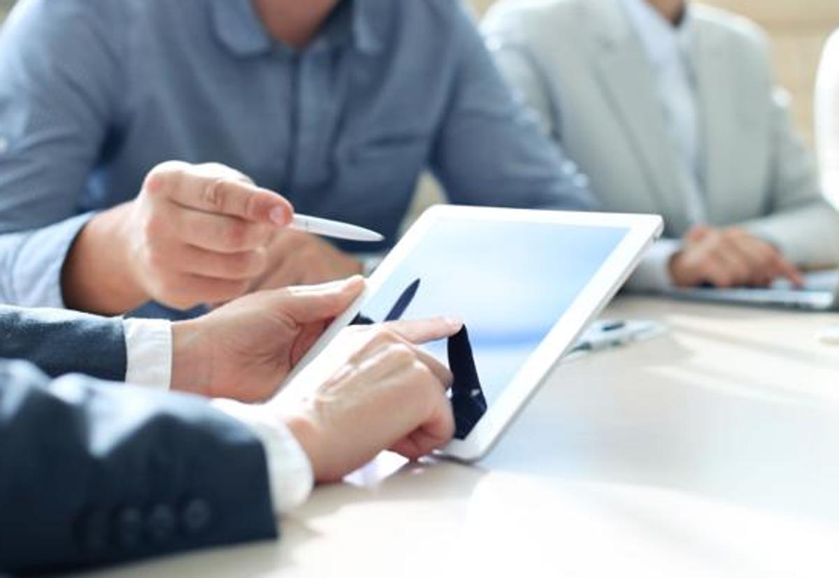 Un grupo de emprendedores consulta información en un dispositivo electrónico.