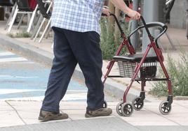 Una persona mayor camina por la calle con ayuda de un andador.