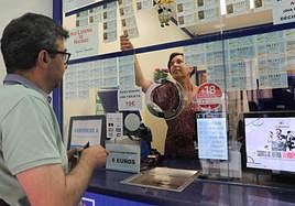 Ana Feijóo, de la administración La Gorda, atiende a un cliente que compra lotería de Navidad.