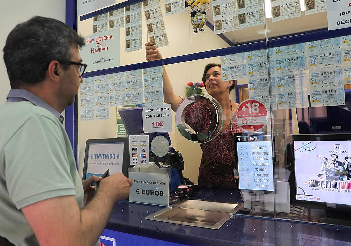 Ana Feijóo, de la administración La Gorda, atiende a un cliente que compra lotería de Navidad.