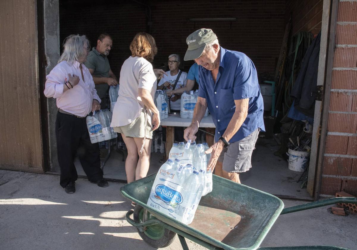 Un vecino de Juarros de Voltoya coloca en su carretilla dos paquetes de botellas de agua.