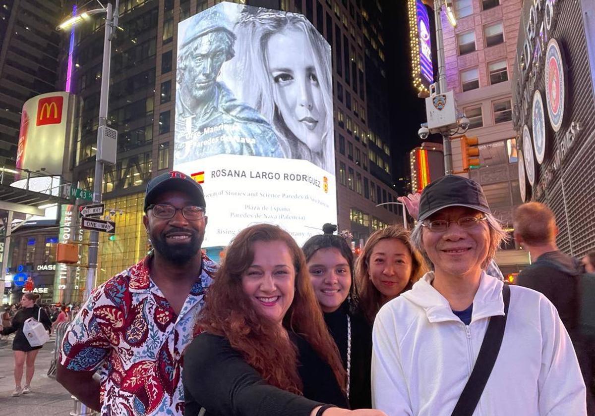 Unos turistas se fotografían en Times Square con la imagen de Rosana Largo y Jorge Manrique de fondo.