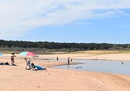 Sombrillas, toallas extendidas y bañistas en el pantano de Aguilar.