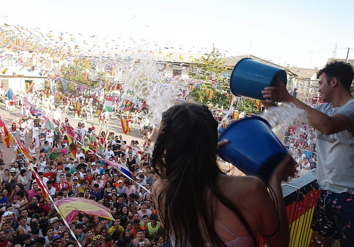Dos jóvenes lanzan agua a los asistentes al chupinazo de las fiestas.
