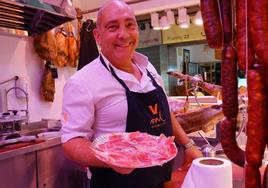 Felipe González muestra en su charcutería un plato con trozos de jamón ibérico.