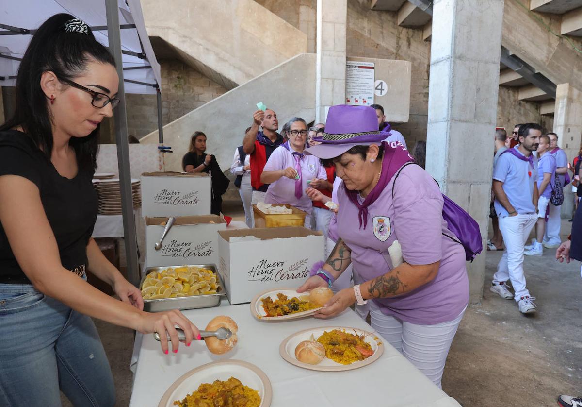 Una palentina de la peña Despenaos coge su ración de paella.