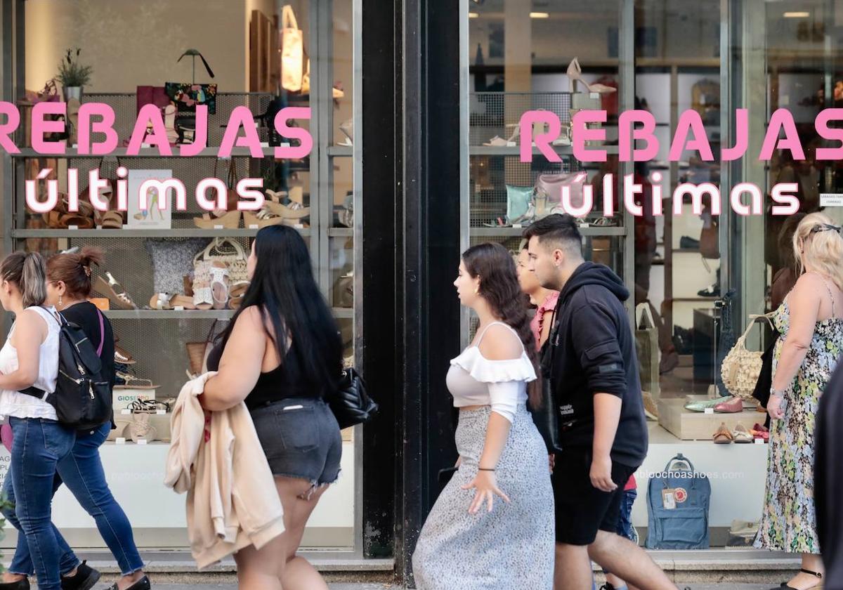 Varias personas pasean delante de un escaparate en Valladolid, en las últimas horas de rebajas.