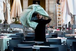 Un camarero prepara las mesas de una terraza.