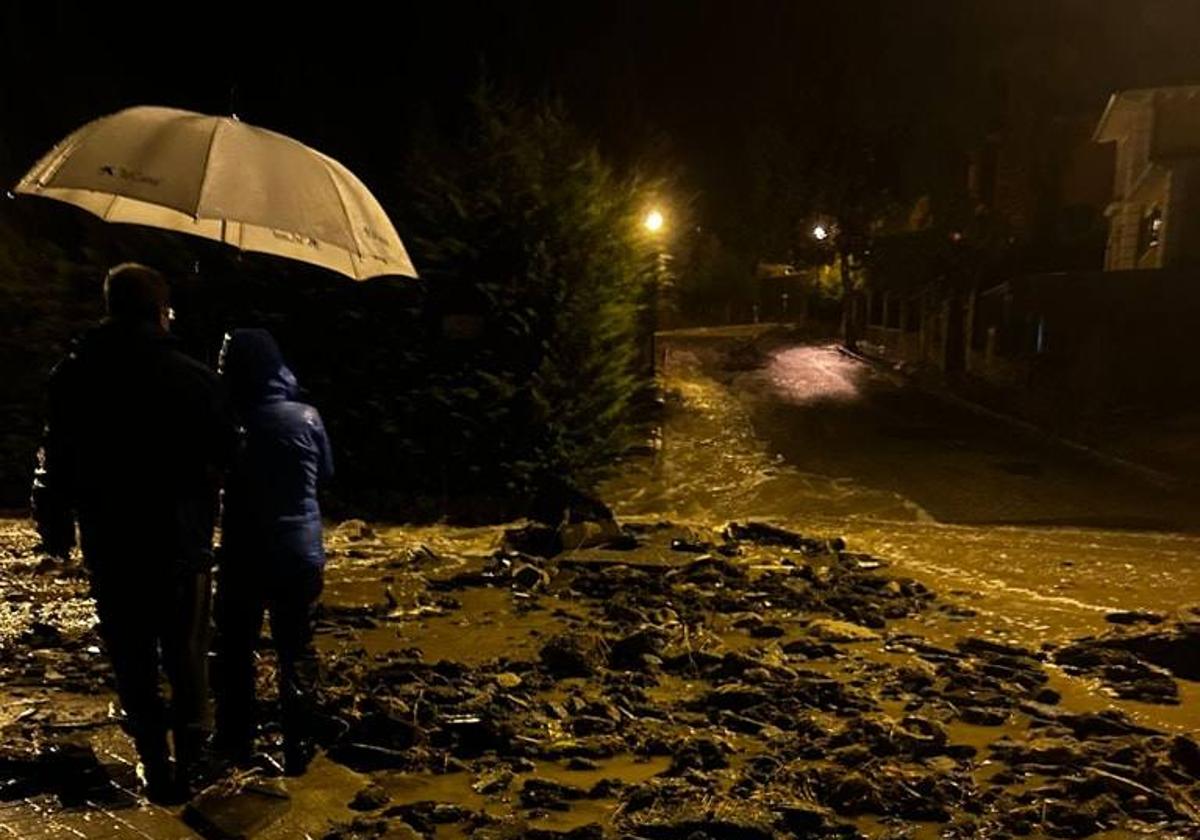 Dos vecinos observan la riada por una calle de El Espinar.