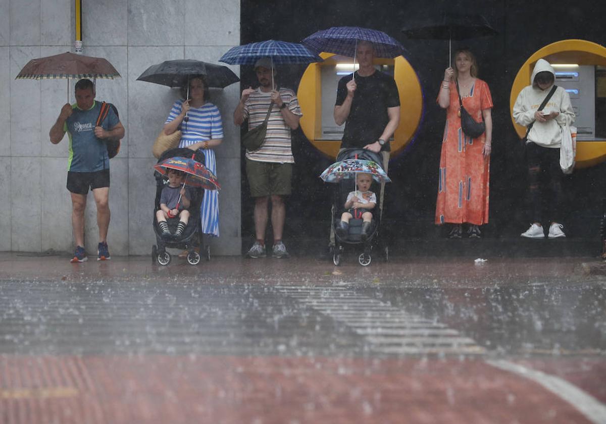 Varias personas se refugian de la lluvia en Valencia.