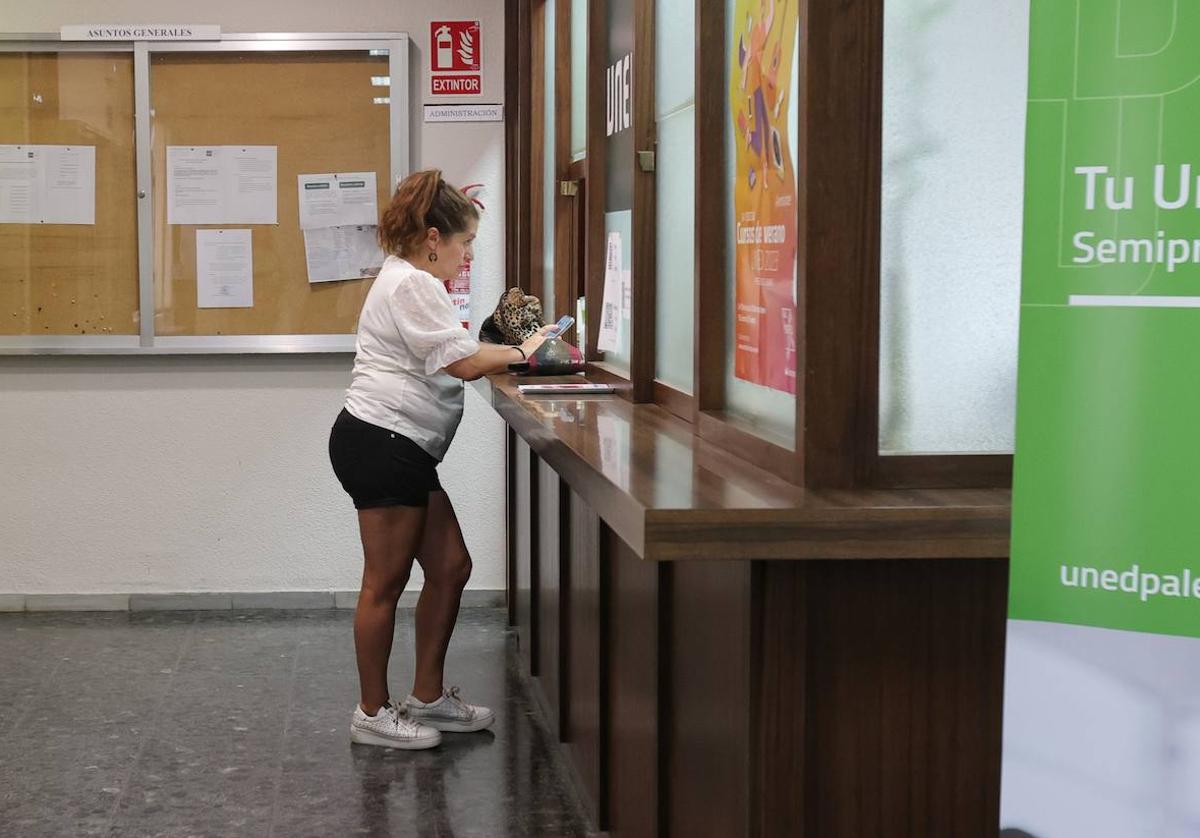 Una mujer recibe información de la UNED en la zona de admisión del centro.