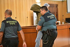 El preso abandona la sala de vistas escoltado por la Guardia Civil tras el juicio.