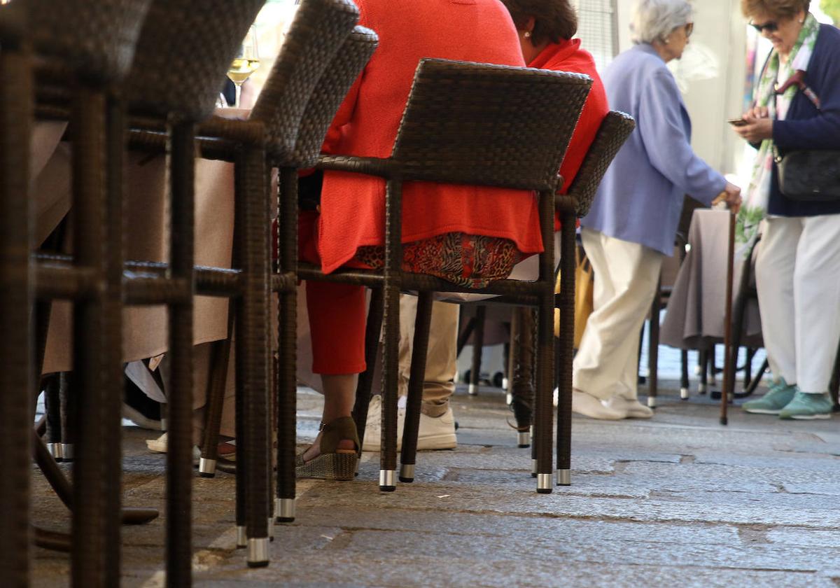 Varias personas sentadas en una terraza, cuyas sillas sobresalen de los límites de ocupación marcados.