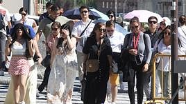 Un grupo de personas camina por la ciudad con paraguas para resguardarse del sol.