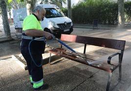 Un trabajador de la limpieza elimina la suciedad de un banco.