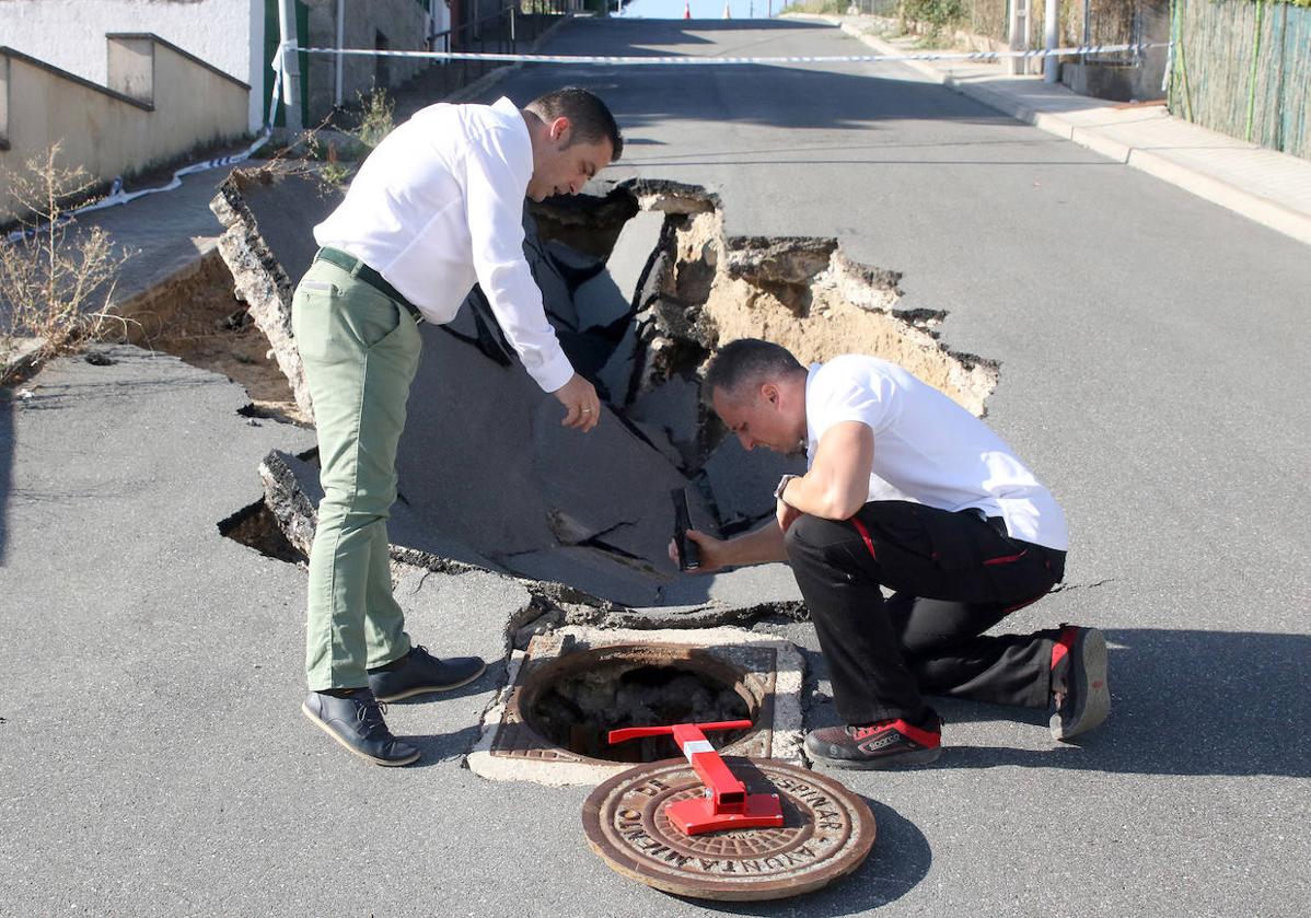 Imagen principal - Arriba, el alcalde, Javier Figueredo, comprueba junto a un trabajador municipal una tubería taponada, frente a un socavón en San Rafael. Abajo, montaña de mobiliario dañado por las inundaciones y, a la derecha, operarios durante las labores de reparación del firme.