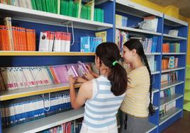 Dos niñas del CEIP Tierra de Pinares de Mojados buscan libros en la biblioteca