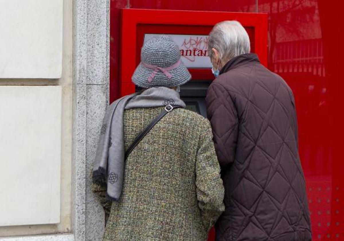 Dos personas sacan dinero de un cajero automático.