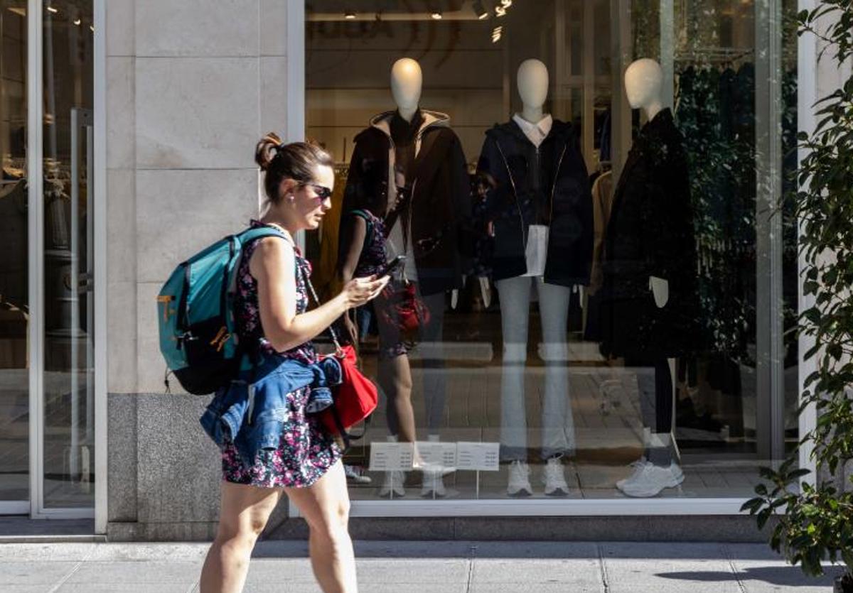 Una mujer pasea ante un escaparate que muestra ropa de abrigo en la calle Santiago.