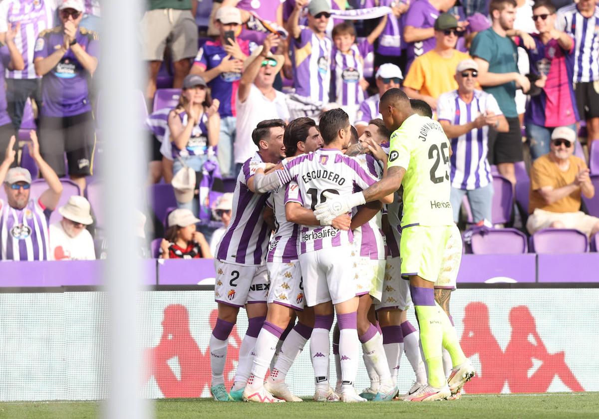 Los jugadores del Real Valladolid celebran el gol frente al Mirandés abrazados, con los aficionados aplaudiendo de fondo.