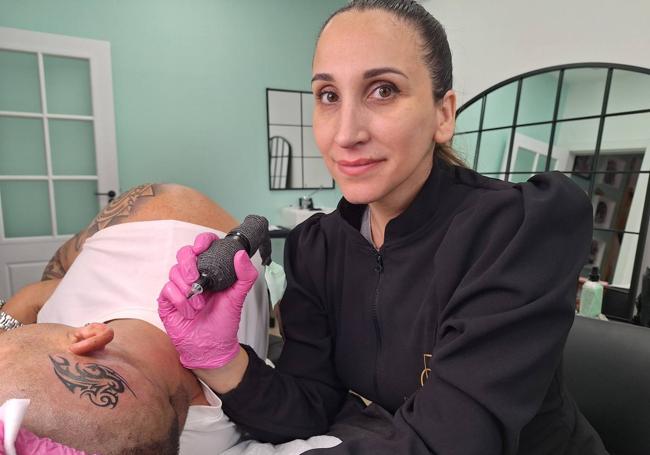 Diana realizando un tatuaje a uno de sus clientes