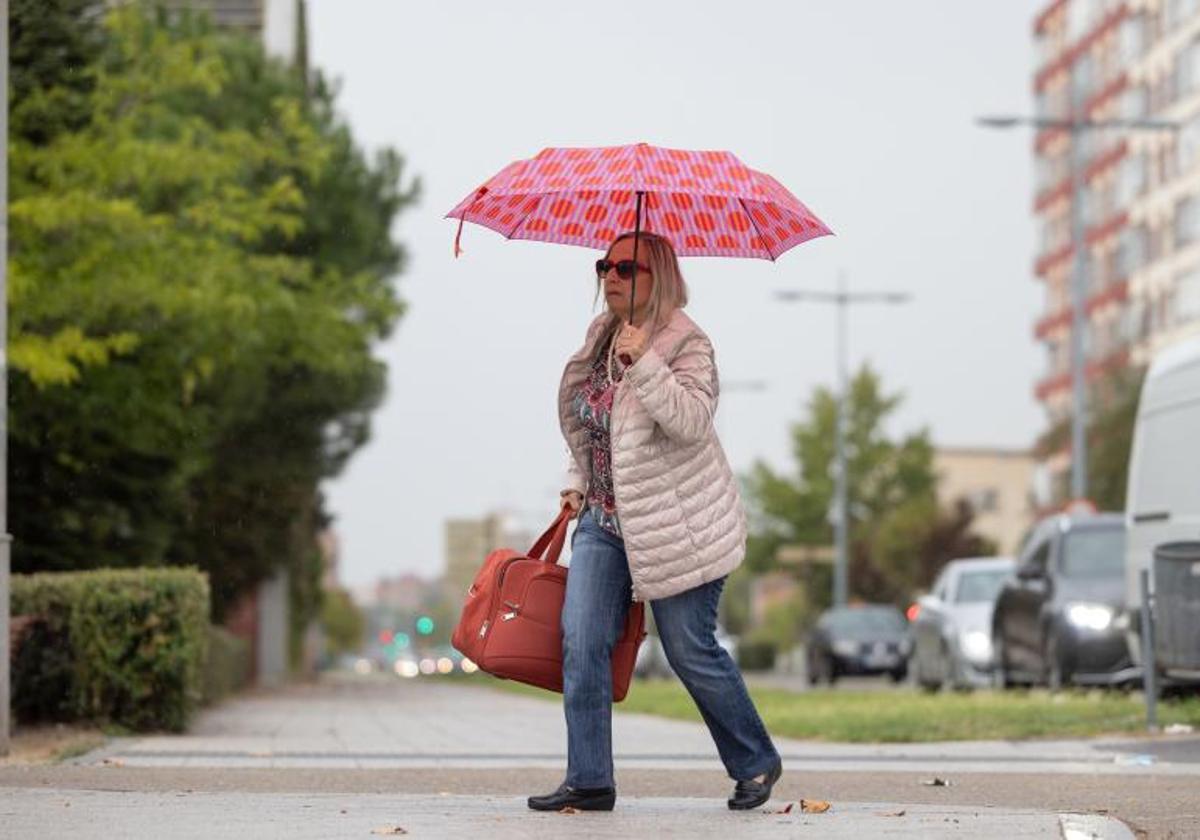 Las primeras gotas obligaron a sacar el paraguas el viernes en Valladolid. En la imagen, una mujer se protege de la lluvia en Isabel La Católica.