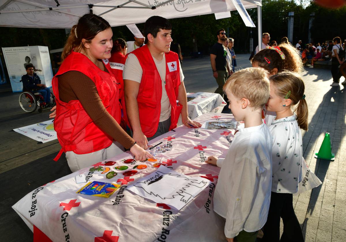 Varios niños, junto a voluntarios de Cruz Roja, en la plaza de Zorrilla.