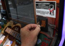 Un hombre echa una moneda a una máquina tragaperras.