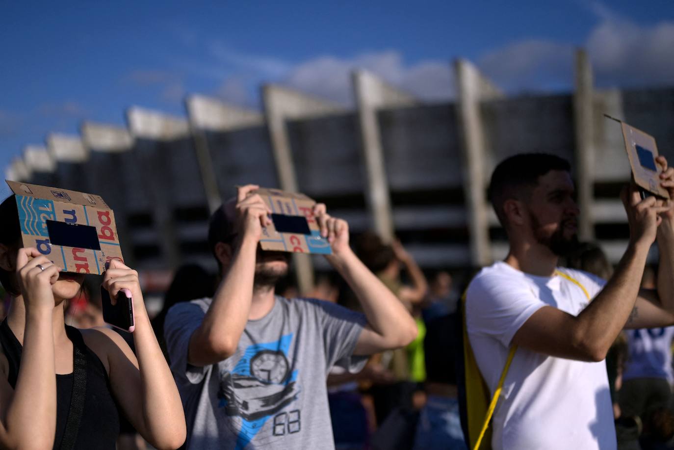 Varias personas observan el eclipse solar desde el Estadio Mineirao, en Brasil. 