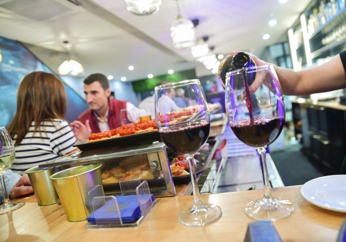 Una camarera sirve dos vinos tintos en un bar restaurante de Valladolid.