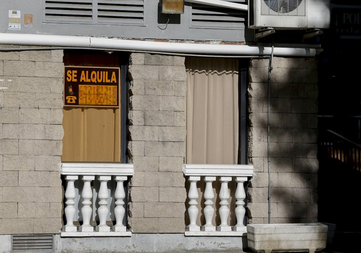 Cartel que anuncia el alquiler en la ventana de una vivienda.