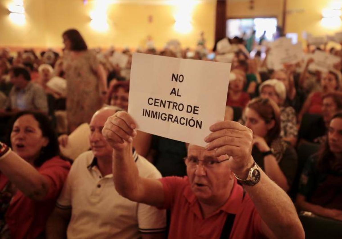 Un hombre exhibe un cartel en el que rechaza la construcción de un centro de refugiados en Las Delicias.