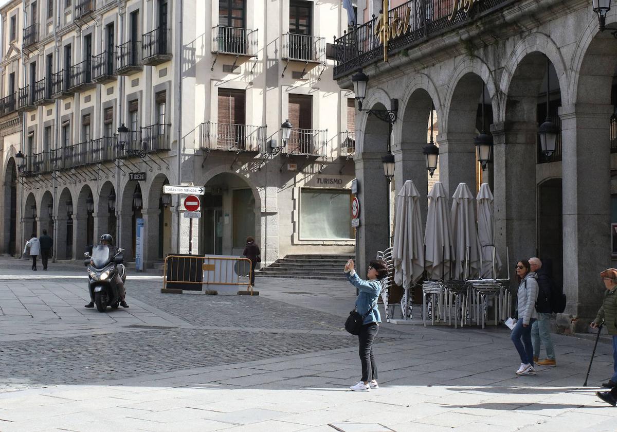 Una mujer hace una fotografía en la Plaza Mayor, sin vehículos estacionados.