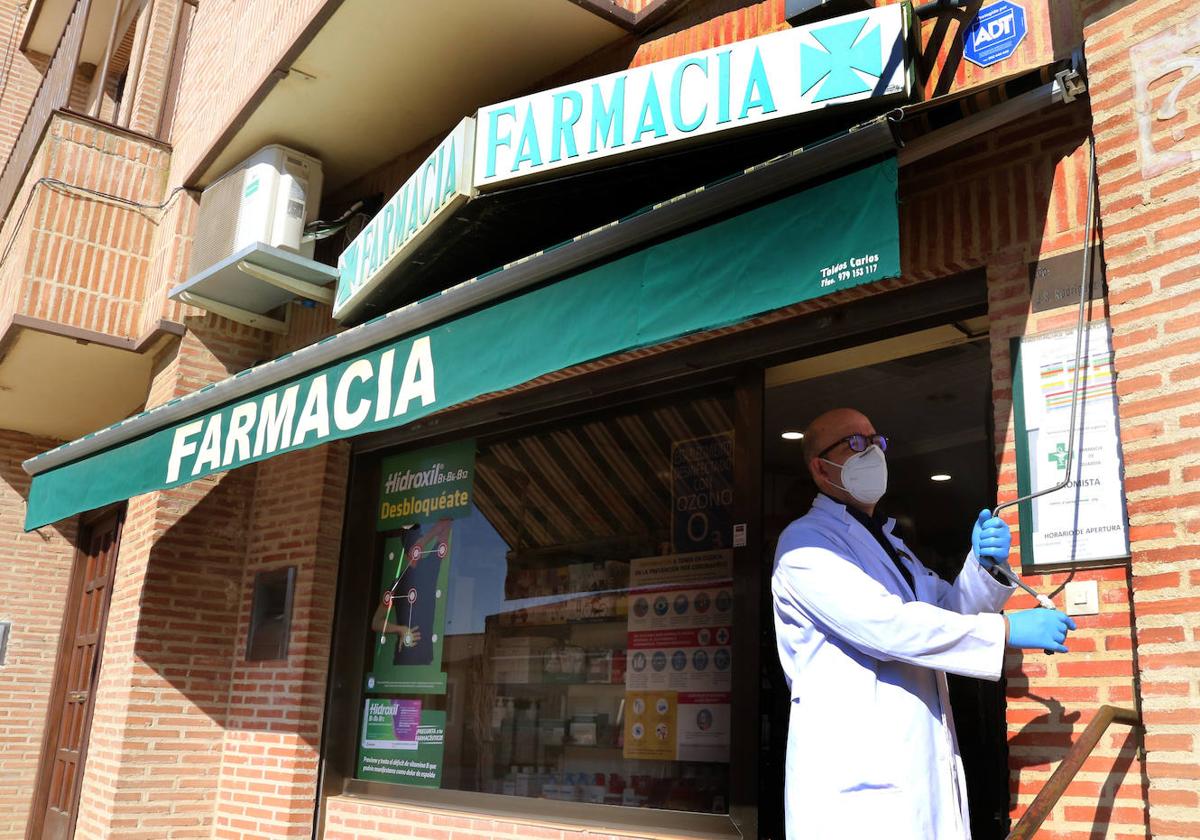 Un farmacéutico baja el toldo en una botica de la provincia.