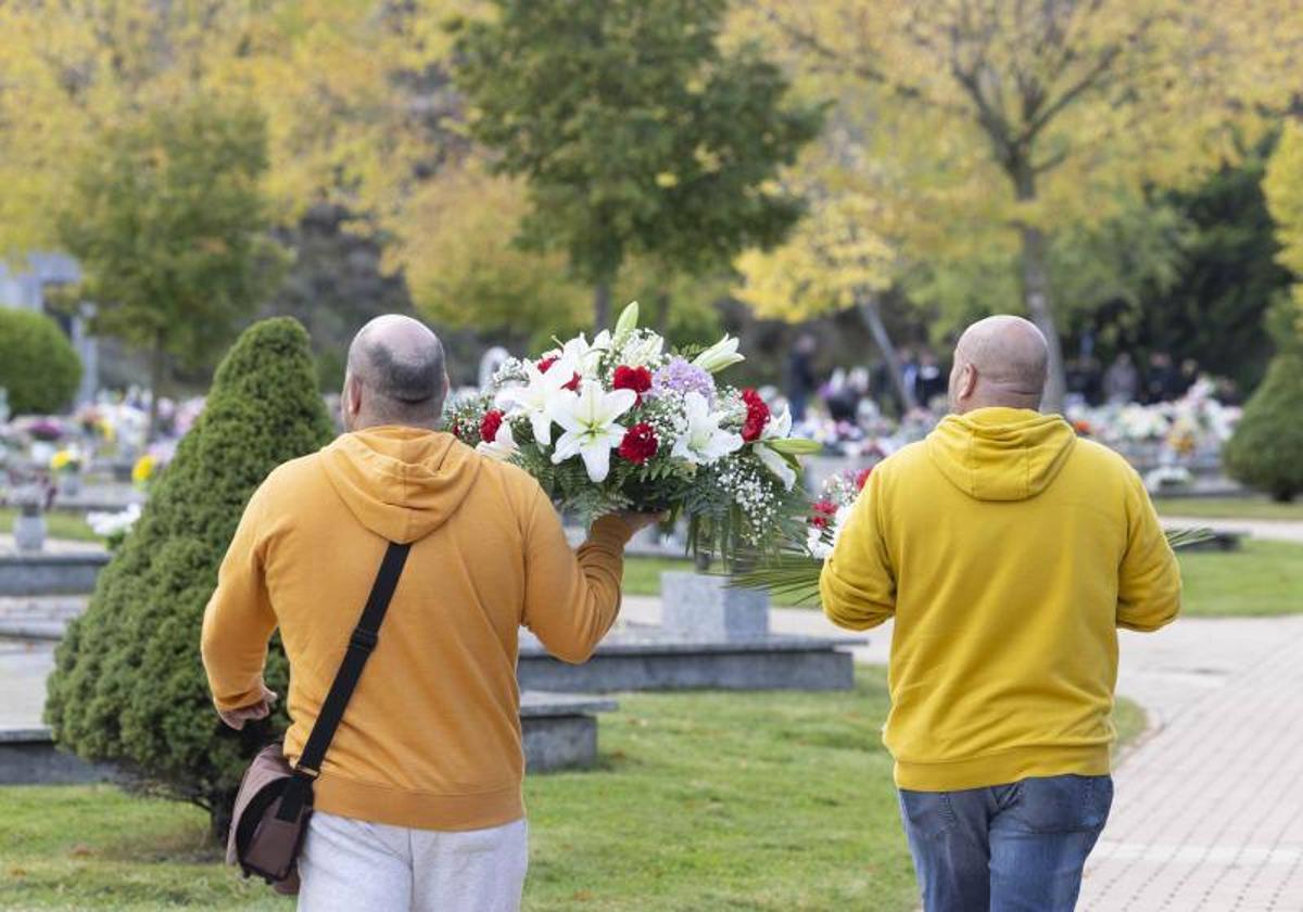 Dos hombres llevan un centro de flores por el Día de Todos los Santos en un cementerio de Valladolid, el año pasado.